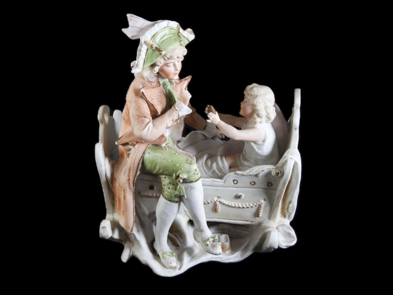 FIGURA MASCULINA SENTADA SOBRE BERÇO